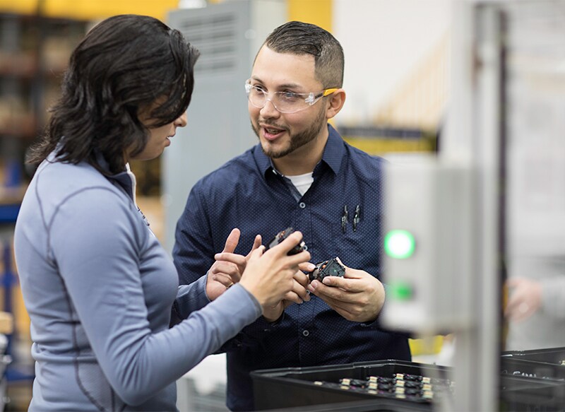 Two Stanley Black & Decker employees engaged in a conversation about product in a manufacturing facility