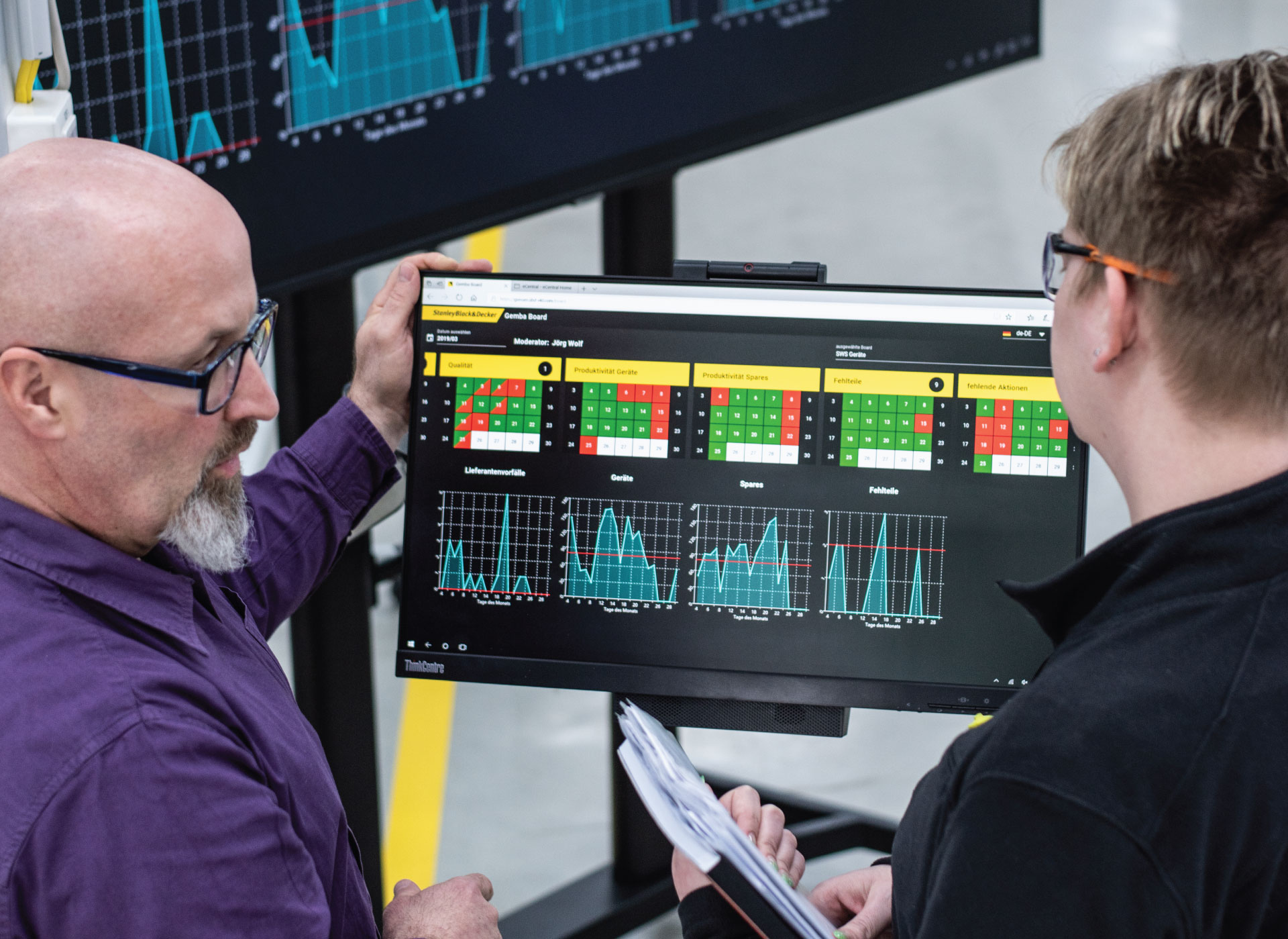 Two Stanley Black & Decker employees working over a monitor