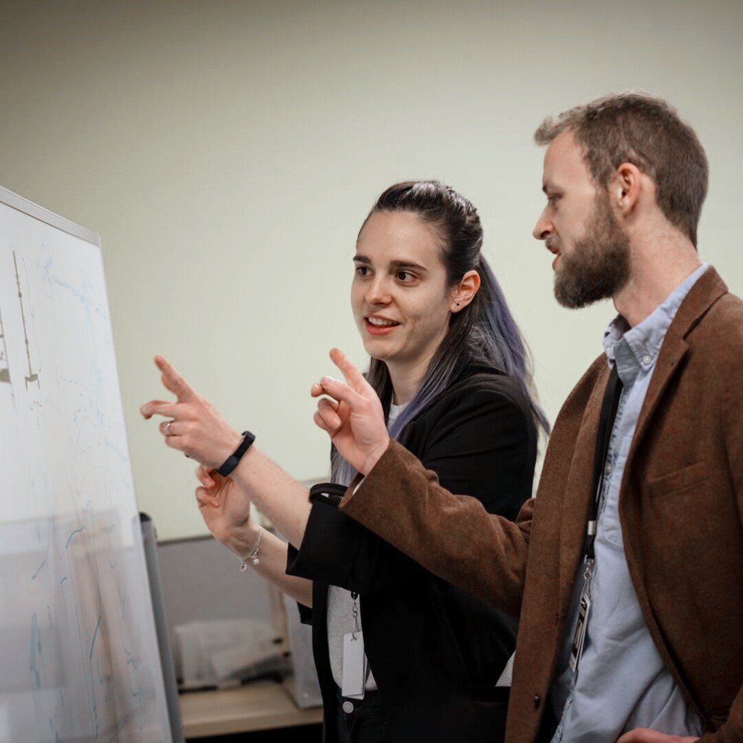 Two employees brainstorming around a whiteboard